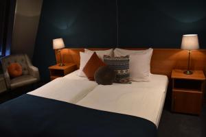 a bedroom with a large bed with pillows and a chair at Hotel De Vrouwe van Stavoren in Stavoren