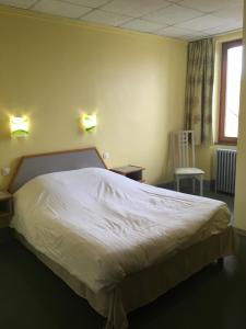 ein Schlafzimmer mit einem großen Bett in einem Zimmer mit einem Fenster in der Unterkunft Hostellerie d'Alsace in Cernay