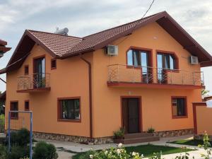 a house with orange paint and a brown roof at Pensiunea Cosmin in Corbu