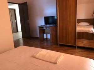 a bedroom with a bed and a desk with a television at Pensiunea Cosmin in Corbu
