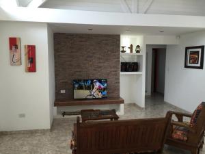un salon avec une télévision sur un mur en briques dans l'établissement Casa Patagónica Los Frutales, à El Calafate