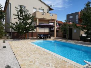 a swimming pool in front of a house at Holiday Retreat Apartment - Zadar in Zadar