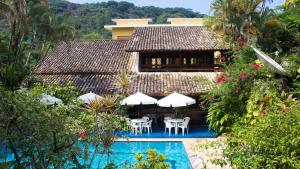 a resort with a swimming pool with chairs and umbrellas at Pousada Albatroz in Ubatuba