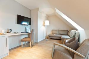 a living room with a couch and a tv at Best Western Plus Theodor Storm Hotel in Husum