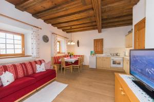 a living room with a red couch and a kitchen at Oberdeutinghof in Saalfelden am Steinernen Meer
