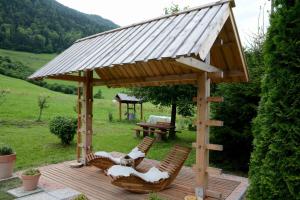 a wooden gazebo with two chairs and a table at Studio ALPIKA in Luče