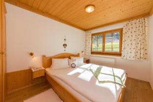 a bedroom with a large white bed with a window at Oberdeutinghof in Saalfelden am Steinernen Meer