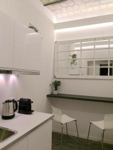 een keuken met witte werkbladen en stoelen en een raam bij Luxury rooms near Colosseum in Rome
