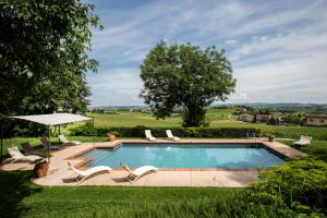 a swimming pool in a yard with chairs and a tree at Relais I Castagnoni in Rosignano Monferrato