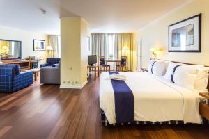 a hotel room with a large bed and a living room at Holiday Inn Lisbon by IHG in Lisbon