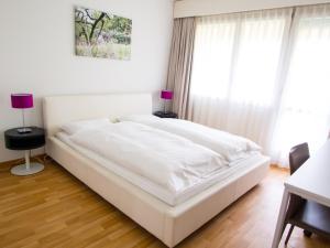 a large white bed in a room with windows at CITY STAY - Ringstrasse in Brüttisellen