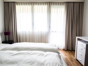a bedroom with white curtains and a bed and a dresser at CITY STAY - Ringstrasse in Brüttisellen +6 photos