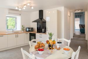 a white kitchen with a table with food on it at Occitanie Aquitaine gîte 5 pers -SPA privé-CLIM- Draps, vélos inclus - Equipé pour bébé in Soturac