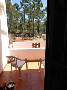 a balcony with a chair and a bench on a porch at Patio Beach House - Checkinhome in Castro Marim