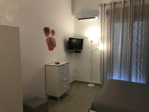 Schlafzimmer mit einem Bett, einem TV und einer Kommode in der Unterkunft Appartamento Le Tre Rose in Trapani