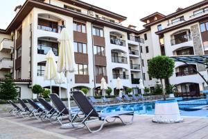 un hôtel avec des chaises et des parasols à côté d'une piscine dans l'établissement Sea Club Sarafovo Apartments, à Bourgas