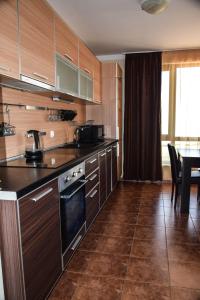 une cuisine avec des placards en bois et une salle à manger dans l'établissement Sea Club Sarafovo Apartments, à Bourgas