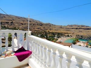 a white balcony with a table with a pink pillow at New Lindos Studio 45 renovated in Líndos