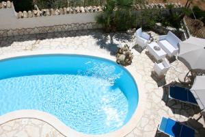 an overhead view of a swimming pool with white chairs at Hotel Il Cortile in Custonaci