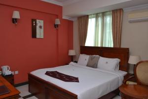 - une chambre avec un grand lit blanc aux murs rouges dans l'établissement Hotel Nikko Towers, à Dar es Salaam