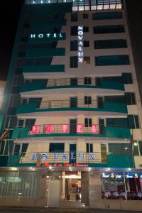 un edificio alto con un cartel en él por la noche en Hotel Novalux, en Ambato