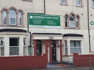 un bâtiment avec un panneau indiquant une maison d'hôtes en forme de shampooings dans l'établissement Shamrock Guest House, à Gravesend