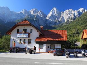 a building with motorcycles parked in front of it with mountains at Apartments and Rooms Jozica in Kranjska Gora