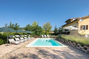 a pool with chairs and umbrellas next to a house at Country House Villa Sabrina in San Ginesio