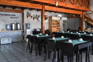 un restaurant avec des tables et des chaises noires dans une salle dans l'établissement Hotel Acantilado, à Las Grutas