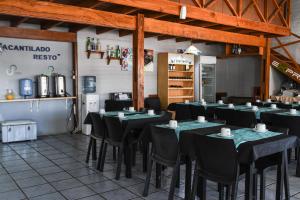 a restaurant with black tables and chairs in a room at Hotel Acantilado in Las Grutas