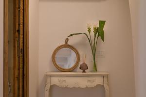 a table with a mirror and a vase with flowers on it at Casa Regina Paola in Monopoli