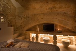 a room with a stone wall with a tv and a table at Casa Regina Paola in Monopoli