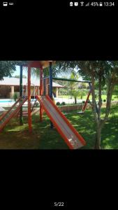a playground with a red slide in a park at Chacara Recanto dos Passaros 01 in Olímpia