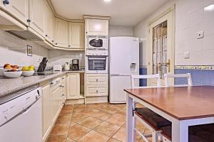 cocina con electrodomésticos blancos y mesa de madera en Beferent Riviera Blanca Golf - Playa, en Alicante