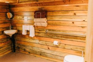 a bathroom with a wooden wall with a toilet and a sink at The Yurt at Rivendell in White Salmon