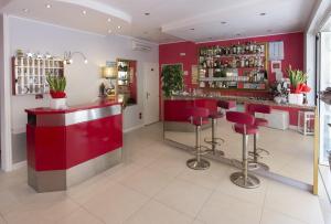 un bar en un restaurante con paredes rojas y taburetes en Hotel Atene, en Lido di Jesolo