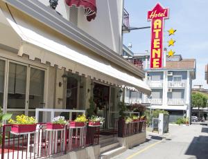 un ristorante in una strada con un cartello e fiori di Hotel Atene a Lido di Jesolo