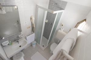 y baño blanco con ducha, aseo y lavamanos. en Hotel Atene, en Lido di Jesolo