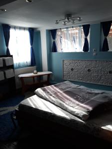 sypialnia z łóżkiem z niebieskimi ścianami i oknami w obiekcie Jaky residence cu terasă w Braszowie