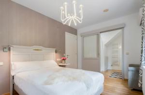 ein Schlafzimmer mit einem weißen Bett und einem Kronleuchter in der Unterkunft El jardí de l'avet in Lleida