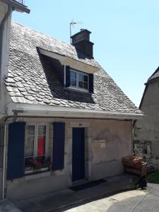 ein altes Haus mit blauen Türen und einem Dach in der Unterkunft maison cosy proche de la station de ski du lioran 4 personnes in Thiézac