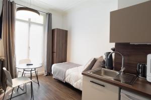 una cocina con fregadero y una cama en una habitación en Les cles du 27 Paris, en París