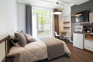 a bedroom with a bed and a kitchen and a window at Les cles du 27 Paris in Paris