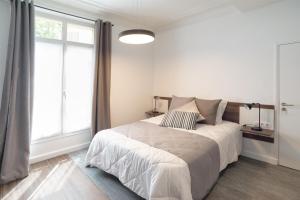 a white bedroom with a bed and a window at Les cles du 27 Paris in Paris