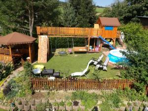 a small backyard with a playground with a house at Domek nad Potokiem in Słotwiny