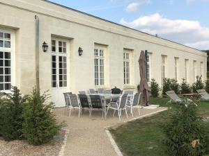 uma mesa com cadeiras e um guarda-sol em frente a um edifício em maison d'hôtes de l'orangerie 14 personnes em Azay-sur-Cher