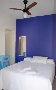 a blue bedroom with a white bed with a ceiling fan at Hotel Gandhi in Jacutinga
