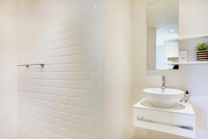 a white bathroom with a sink and a mirror at Cheviot Place Garden Apartment with Private Entrance in Cape Town