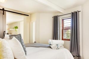 a bedroom with a white bed and a window at Cheviot Place Garden Apartment with Private Entrance in Cape Town