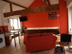 una sala de estar con una pared roja con un piano en The Dairy at Lodge Farm, en Norwich